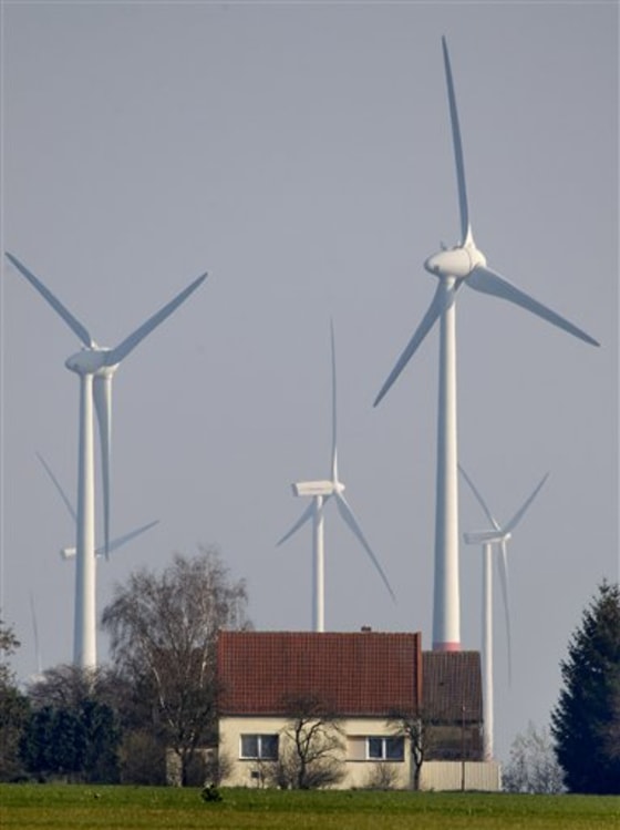 In this photo taken Nov. 12, 2011, wind turbines stand behind houses of the village of Feldheim near Berlin, Germany. This tiny village of 37 gray homes and farm buildings clustered along the main road in a windswept corner of rural eastern Germany seems an unlikely place for a revolution. Yet environmentalists, experts and politicians from El Salvador to Japan to South Africa have flocked here in the past year to learn how Feldheim, a village of just 145 people, is already putting into practice Germany's vision of a future powered entirely by renewable energy. Chancellor Angela Merkel's government passed legislation in June setting the country on course to generate a third of its power through renewable sources _ such as wind, solar, geothermal and bioenergy _ within a decade, reaching 80 percent by 2050, while creating jobs, increasing energy security and reducing harmful emissions.The goals are among the world's most ambitious, and expensive, and other industrialized nations from the U.S. to Japan
